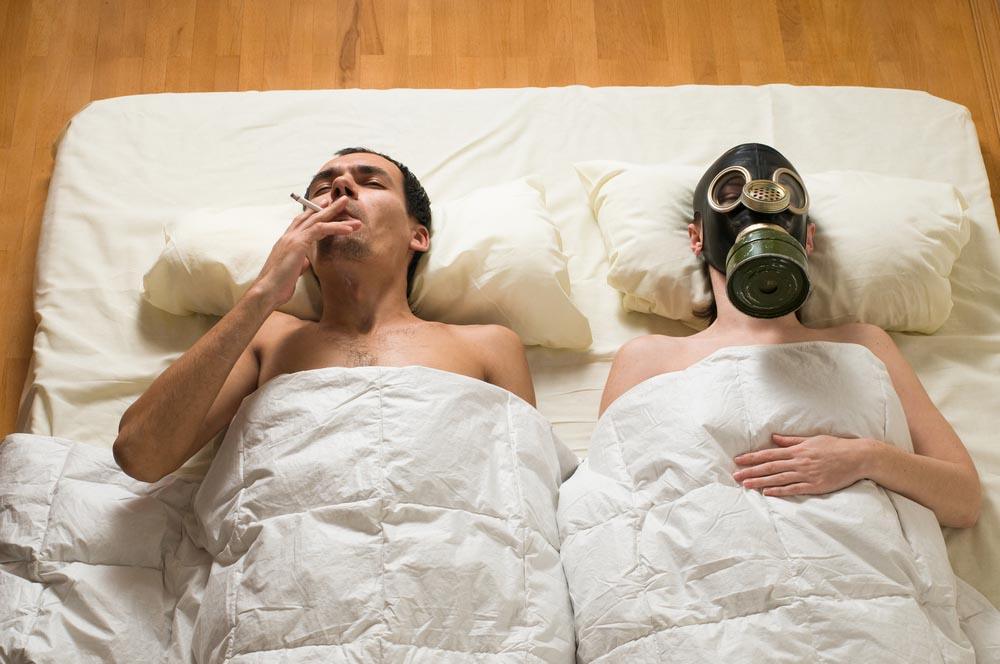 Zigarettengeruch und Nikotingeruch entfernen, Mann und Frau mit Gasmaske im Bett.